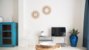 A modern living room with a TV, a blue cabinet, a white chair, and two wall decorations.