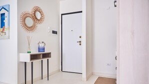 A hallway with a white door, a small table with a vase and a water bottle, and a mirror on the wall. - Cala Coticcio in Golfo Aranci (Golfo Aranci)