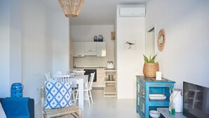 A modern living room with a dining area, a kitchen in the background, and a blue cabinet with decorative items. - Cala Sabina in Golfo Aranci (Golfo Aranci)