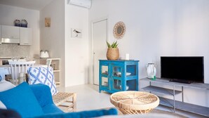 A modern living room with a sofa, a TV, a blue cabinet, and a kitchen area in the background. - Cala Sabina in Golfo Aranci (Golfo Aranci)