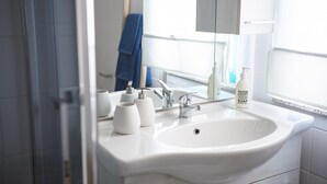 Une salle de bain avec un lavabo blanc, un miroir et un flacon de savon.