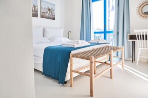 A bedroom with a bed, a bench, a desk, and a window with curtains. - Cala Banana in Golfo Aranci (Golfo Aranci)