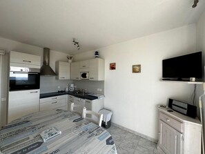 Enjoy cooking and dining in this modern kitchen with oven, microwave, and coffee maker, plus a dining table for meals.