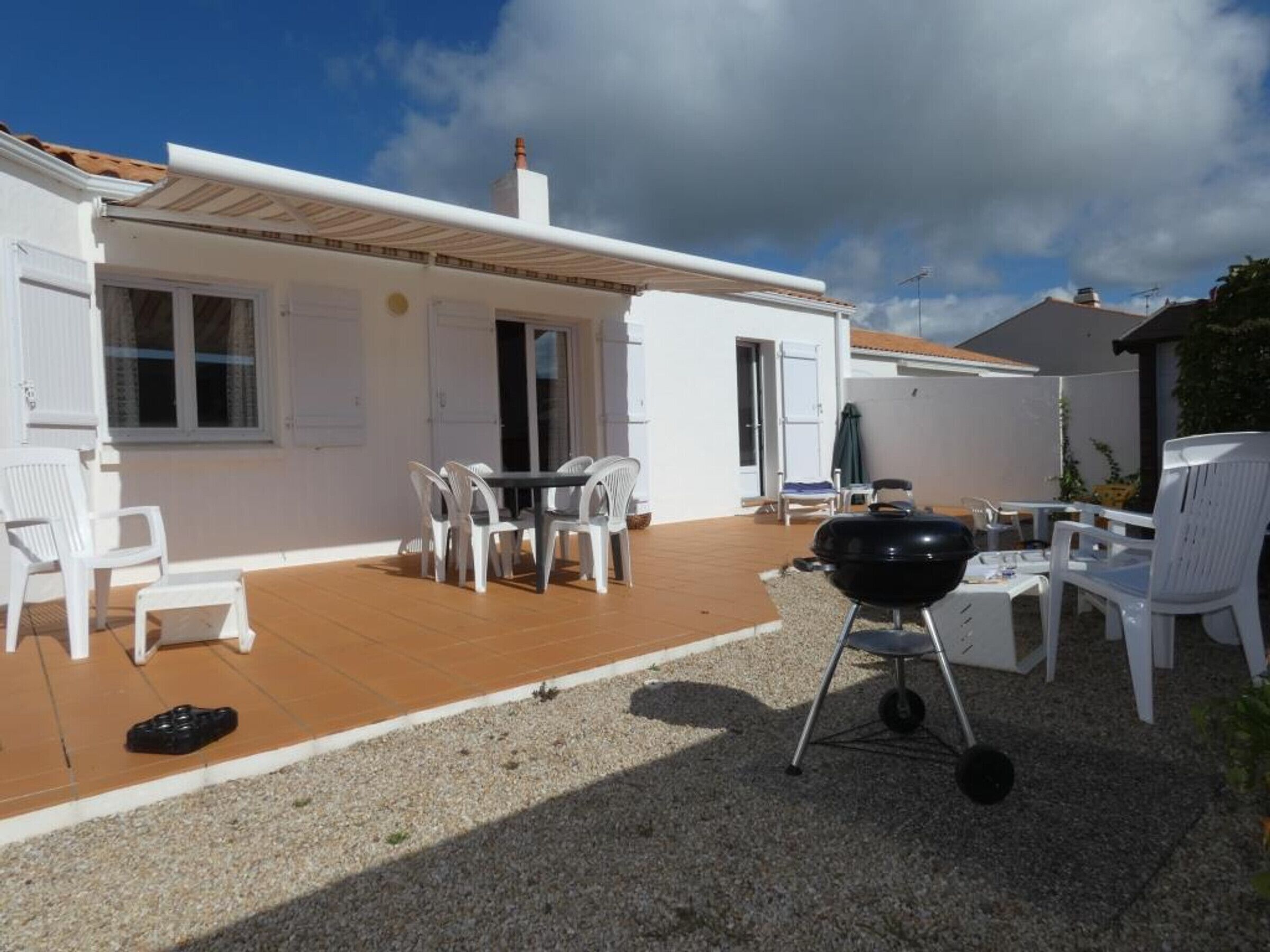 A patio area with a table and chairs, a barbecue grill, and a covered seating area.