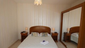 Habitación de hotel con una cama grande, dos mesitas de noche con lámparas, un espejo grande y una lámpara en el techo.
