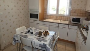 Cocina compacta con comedor, que incluye microondas, horno, pileta y una mesa con sillas y mantel.