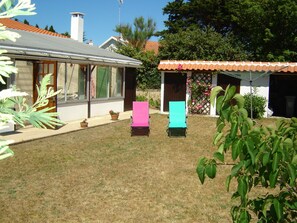 Ein Wohngebiet mit einem Haus, einer Terrasse mit zwei Stühlen und einem kleinen Gartenhaus.