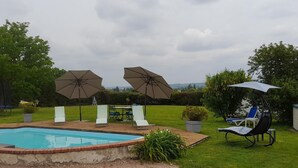 A backyard with a swimming pool, lounge chairs, and umbrellas.