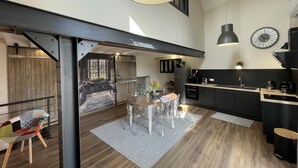 A modern kitchen with a dining area, wooden flooring, and a large window.