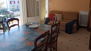 A dining area with a table set for four, a sofa, and a small kitchenette.