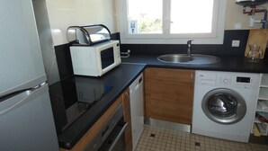 A compact kitchen with a microwave, sink, and washing machine.