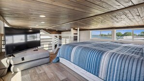 Een slaapkamer met een groot bed, een flatscreen televisie en uitzicht op de omgeving.