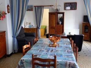 Un comedor con una mesa cubierta con mantel azul, sillas de madera y un cuenco decorativo.
