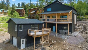 A two-story wooden house with a balcony, a small attached shed, and a gravel driveway.