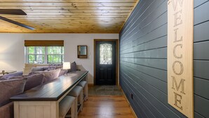 A cozy room with a wooden ceiling, a bench with cushions, a table, and a 'WELCOME' sign on the wall. - Welcome Bow- 6 guest/Hot Tub/Location (Broken Bow)