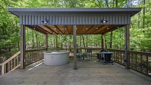 A covered outdoor deck with a hot tub, seating area, and string lights. - Welcome Bow- 6 guest/Hot Tub/Location (Broken Bow)