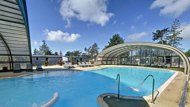 Ein Swimmingpool mit Liegestühlen und einer gläsernen Struktur.