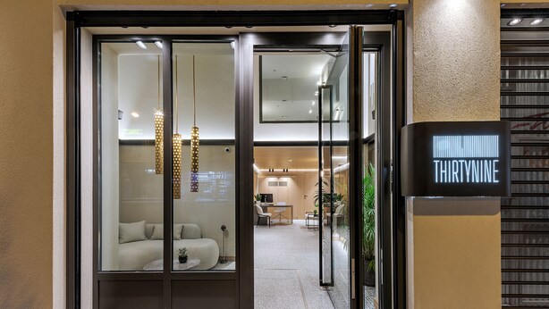 Ein Hotel Eingang mit modernem Design, mit Glastür, einer Rezeption und einem Schild mit dem Namen "THIRTYNINE".