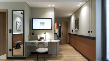 A modern hotel room with a desk, chair, and a large mirror.