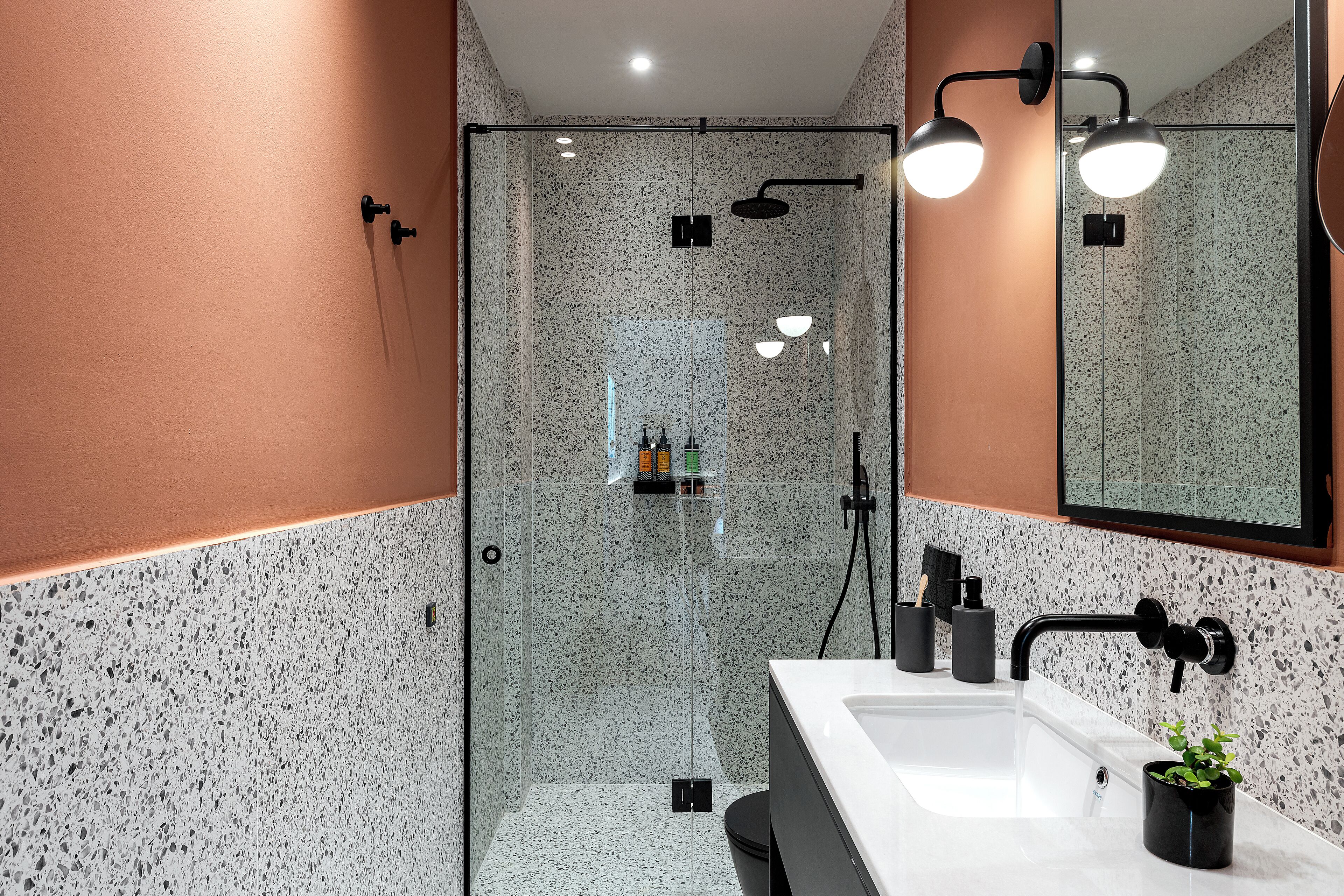 Un bagno moderno con cabina doccia in vetro, lavandino bianco e specchio.