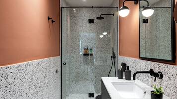 Un bagno moderno con cabina doccia in vetro, lavandino bianco e specchio.