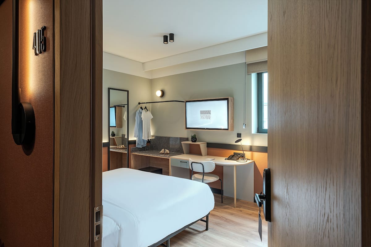 Moderni hotellihuone, jossa on sänky, työpöytä ja peili.