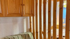 Quarto com guarda-roupa de madeira, sofá riscado e vista através de uma divisória de madeira.