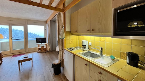 Cozinha moderna com armários de madeira, micro-ondas embutido e uma grande janela com vista para uma paisagem nevada.