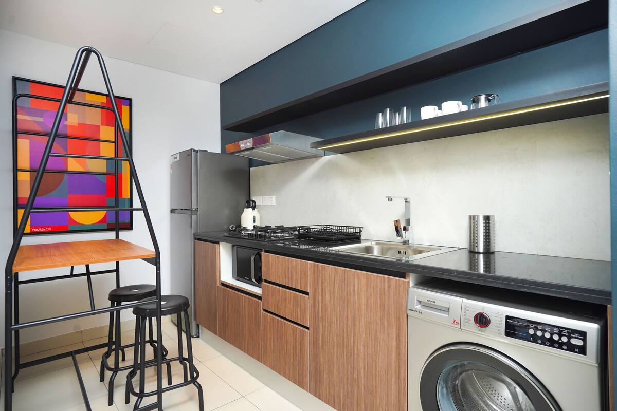 A compact kitchen with a built-in washing machine, a stove, and a sink.