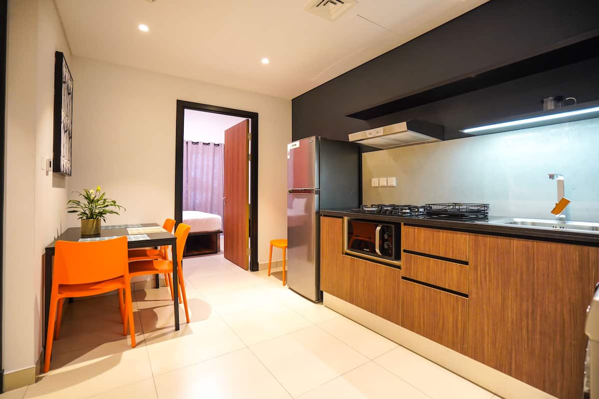 A modern kitchen with wooden cabinets, a built-in microwave, and a stainless steel refrigerator.