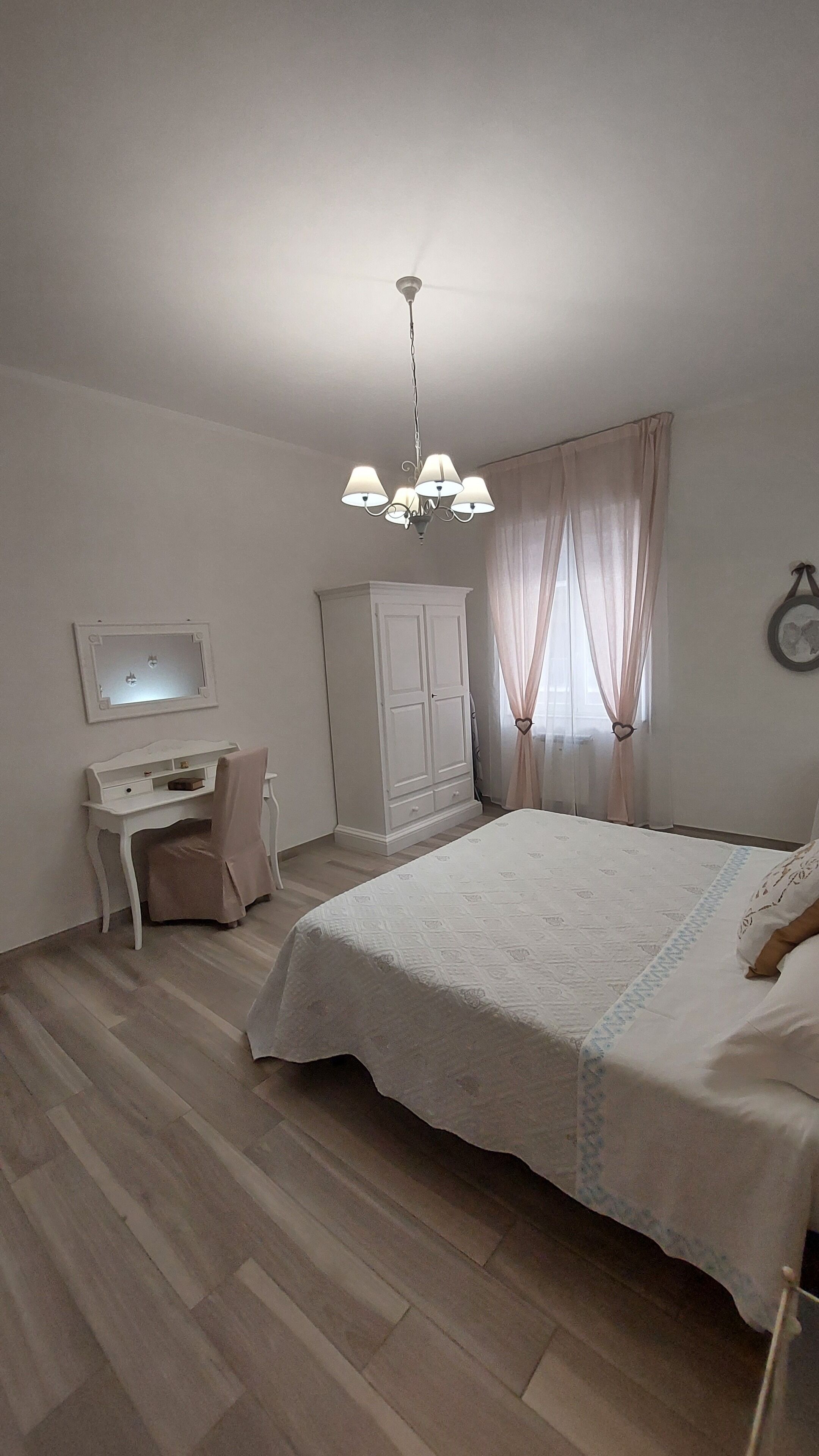 Ein Schlafzimmer mit Bett, Schreibtisch, Kleiderschrank und Deckenleuchte.