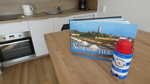 A kitchen with a coffee maker, a kettle, and a book titled "Noirmoutier" on the table. - Seafront Studio at Notre-Dame-de-Monts 2 Pers (Notre-Dame-de-Monts)