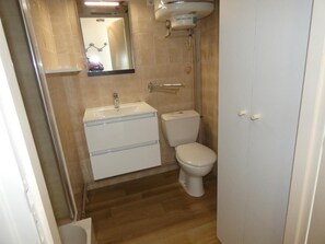 Une petite salle de bain avec des toilettes, un lavabo et un miroir.