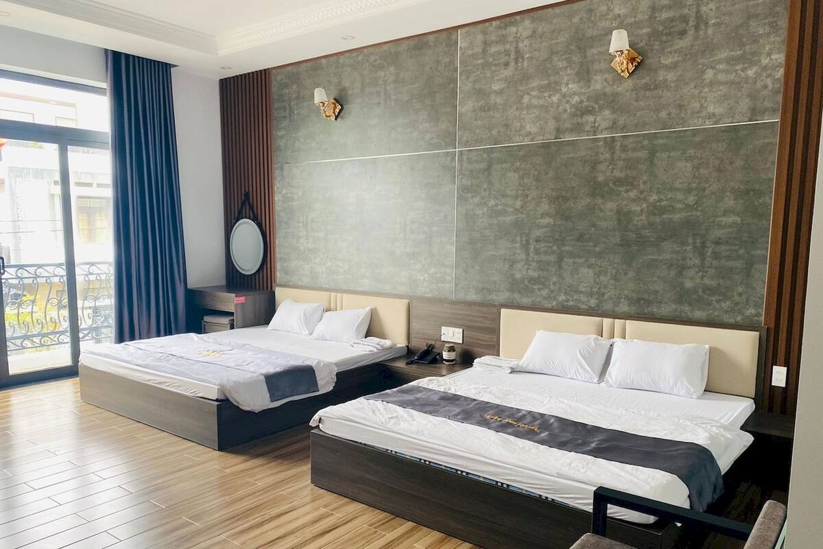 Een hotelkamer met twee bedden, een groot raam en een balkon.