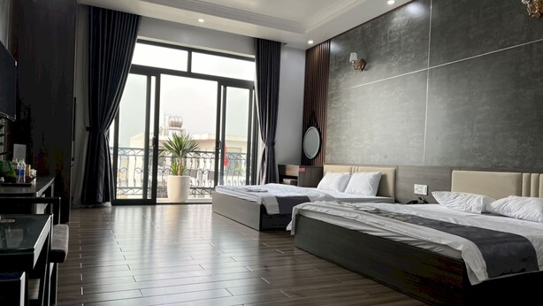 Una habitación de hotel moderna con dos camas, un balcón con vistas y un comedor con mesa y sillas.