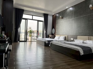 A modern hotel room with two beds, a balcony with a view, and a dining area with a table and chairs. - OYO 1178 Chau Anh Motel (Da Nang)