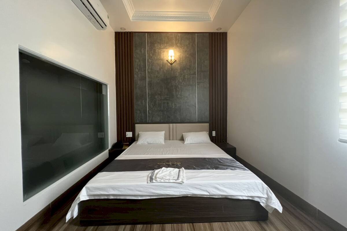 Een moderne hotelkamer met een groot bed, een televisie en een wandlamp.