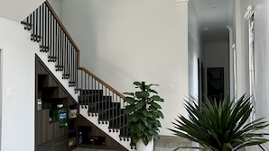 Un interior espacioso con una escalera moderna, suelo de mármol y plantas en macetas.