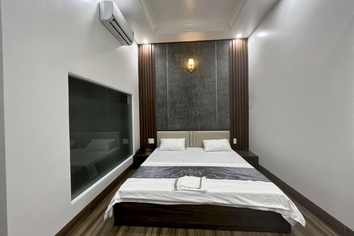 Een moderne hotelkamer met een groot bed, een ingebouwde televisie en een wandairconditioner.