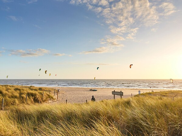 Una playa con dunas cubiertas de hierba y un letrero que indica 'Plage de la Grande Vilette'.