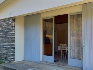 Una entrada de edificio con un muro de piedra, una puerta azul y una pequeña mesa con sillas adentro.