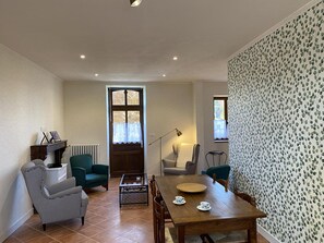 A cozy living room with a wooden dining table, two armchairs, a sofa, and a radiator. - Golf getaway and relaxation at Domaine de Bisseret (Lavault-Sainte-Anne)