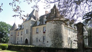 A large, historic stone building with multiple chimneys, arched windows, and a prominent turret. - Golf getaway and relaxation at Domaine de Bisseret (Lavault-Sainte-Anne)