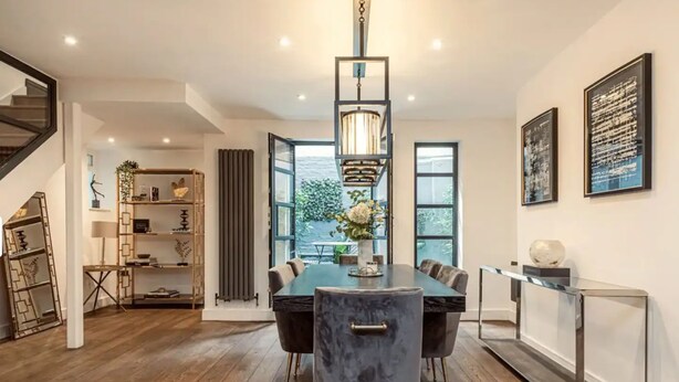 Un espace repas moderne avec une table à plateau en verre, des chaises foncées et un luminaire suspendu.