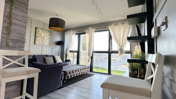 A modern living room with a sofa, a coffee table, and a dining area with chairs. - Canary Wharf two Bedroom Apartment (London)