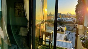 A balcony with a view of the cityscape, a chair, and a small table. - Canary Wharf two Bedroom Apartment (London)