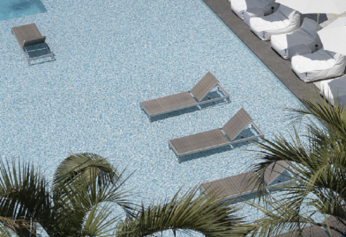 A pool with clear blue water, surrounded by lounge chairs and palm trees.