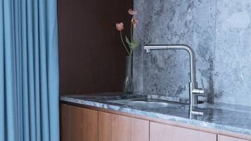 A modern kitchen with a granite countertop, a stainless steel faucet, and a vase with flowers.