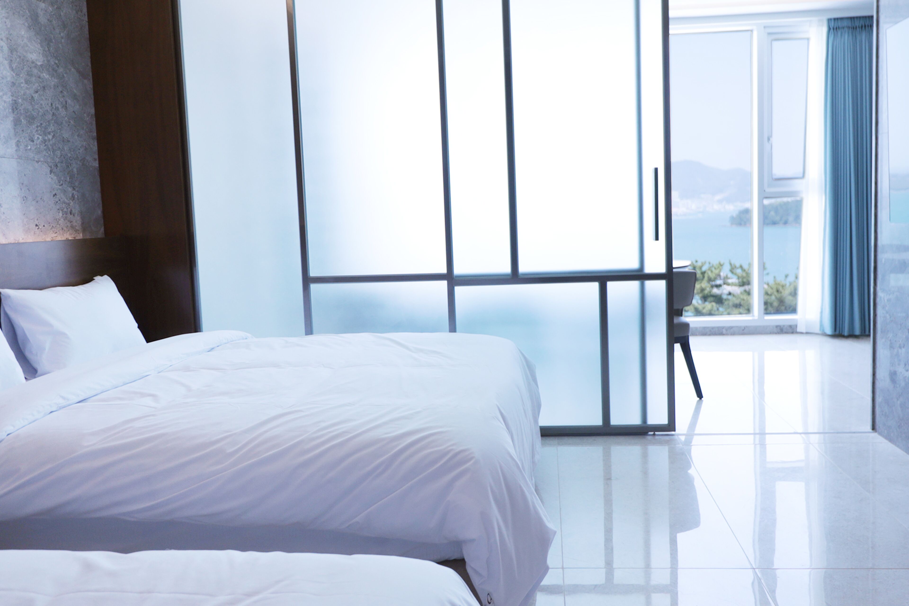 Una habitación de hotel moderna con una cama grande, vistas al mar y un balcón.