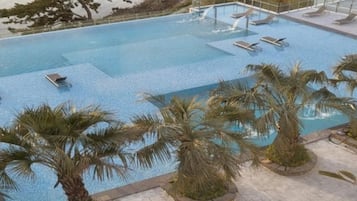 Une piscine avec des chaises longues et des palmiers.